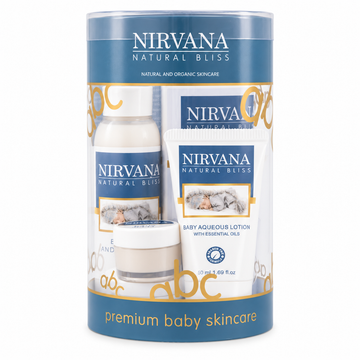 Nirvana Natural Bliss premium baby skincare gift set in a cylindrical blue and white container, containing a bottle of baby astringent lotion, a tube of baby aqueous lotion, and a small jar of cream.