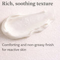 White cream smear on a light background with text about texture and finish for reactive skin.