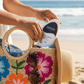 Person putting Nirvana sunscreen into a floral bag on a beach